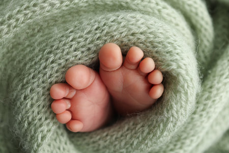 Soft feet of a newborn in a olive green blanket. Close up of toes, heels and feet of a newborn baby.の写真素材