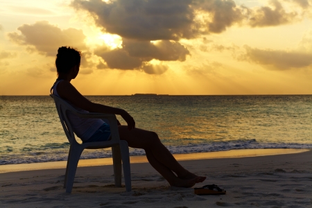 Silhouette of a girl on a chair against a beautiful sunset in the ocean, Maldivesの写真素材