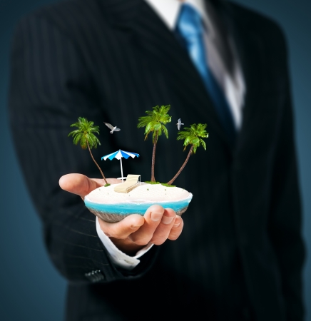 Man holds in his hand a tropical island の写真素材