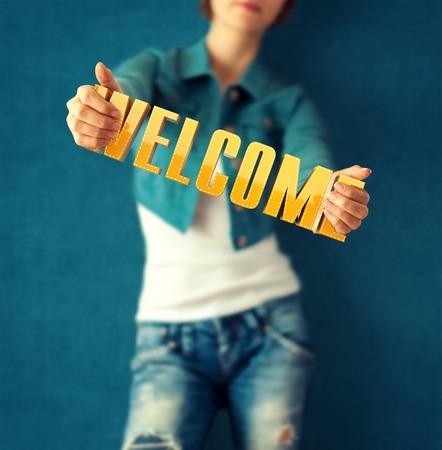 Woman holds word welcome on bright colorful backgroundの写真素材