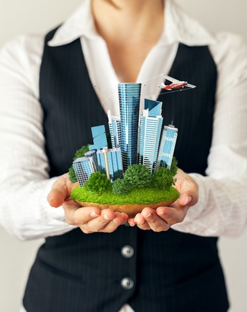 Small fantastic island with a modern city in women's hands.の写真素材