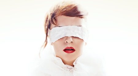 Portrait of attractive woman blindfolded with white paper ribbonの写真素材