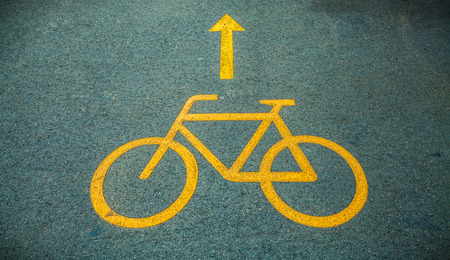 Yellow Bicycle path sign on the asphalt roadの写真素材