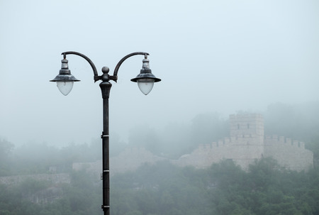 Street lamp and castle wall in fog in Bulgariaの写真素材