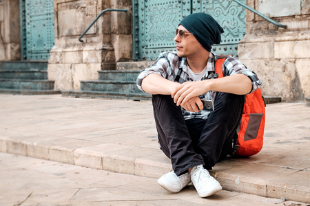 Young handsome man sitting on the floor at the street in a european town.の写真素材