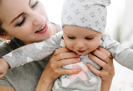Happy smiling mother and baby playing on bed. Happy family having fun.の写真素材