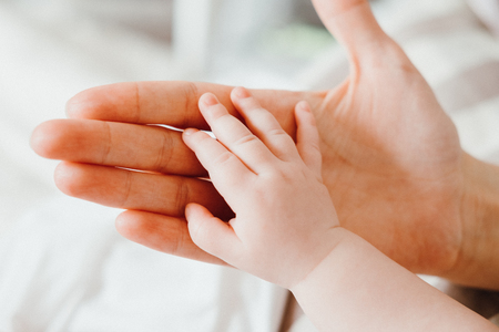 Cute little baby holding mother's hand while sleeping. Happy Family concept.の写真素材