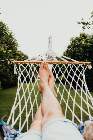 A man has a rest lying on a hammock at tropical garden. Travel and vacation concept.の写真素材