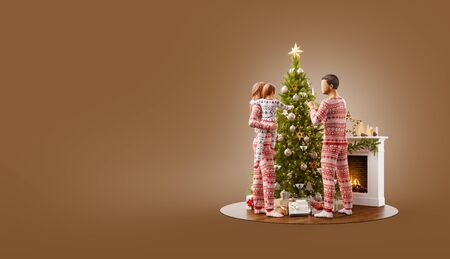 Unusual 3D illustration of happy family decorating a beautiful Christmas tree at fireplace at home. Merry Christmas and Happy New Year concept.の写真素材