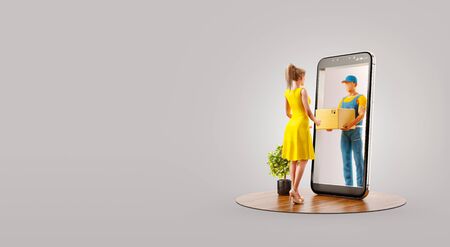 Young woman receiving parcel from delivery service courier through smart phone screen. Unusual 3d illustration. Delivery and post apps concept. Bannerの写真素材