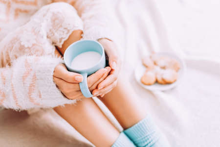 Young woman on the bed with with cup of milk in hands enjoys her stay at home.の写真素材