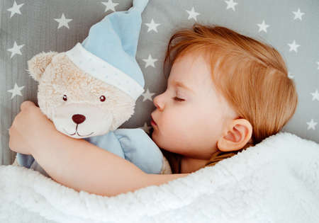 Little baby girl sleeping with her bear toyの写真素材