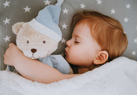 Little baby girl sleeping with her bear toyの写真素材