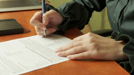 Woman signs a contract. Signature.