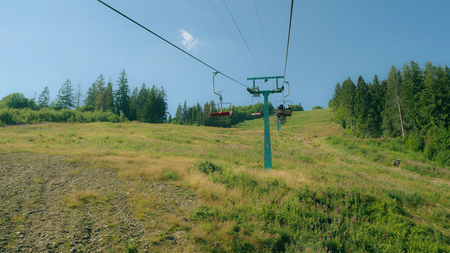 Back view people climb the mountain by cable car in summer season. Beautiful summer landscape with green forest in sunny day.の写真素材