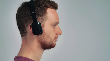close up young man using headphones. young half-face student with red hair listen musicの写真素材