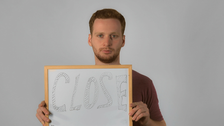 happy caucasian guy with red hair posing showing whiteboard with handwriting close. handsome redhead...