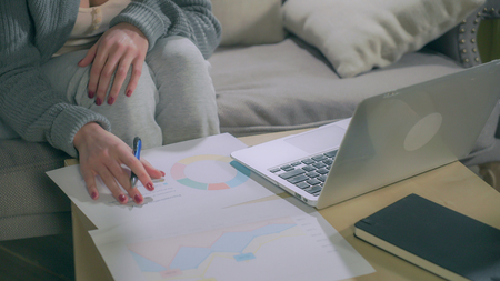 Female hands make notes in charts and laptop. Staticの写真素材