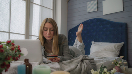 Blond in bed with a laptop spends money. panorama from right to leftの写真素材