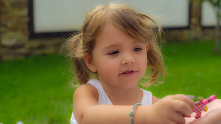 Attractive infant playing with mum on the lawn.Beautiful kid gives mother pencil. Caucasian child 4 years old puts puzzle on mom hand. portrait happy smiling baby play outdoors.の写真素材