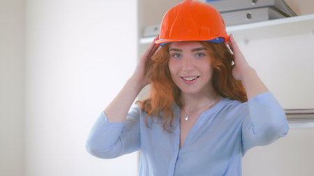 Young redhead woman wearing helmet. Portrait attractive smiling engineer. Female looking at the camera and smiling.の写真素材