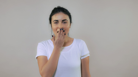forworn caucasian woman with black hair yawns Portrait exhausted young girl wearing casual white t-shirtの写真素材