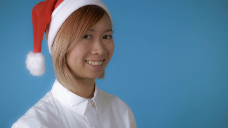 portrait young asian female posing celebrating new year friendly smiling on blue background in studio. attractive korean woman with blond hair wearing white casual shirtの写真素材