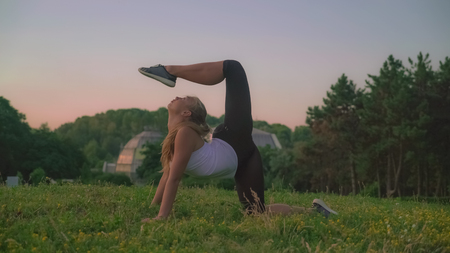 Pilates exercises in the park. Girl enjoy summer doing stretching in the forest with beautiful...