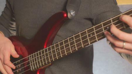 Man playing on the guitar close up. Guy hands pluck the strings on red musical instrument closeup details. guitarist play music on repetitionの写真素材