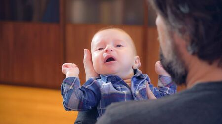 Handsome man with beard holding son. Crying baby in father s arms. Newborn with dad.の写真素材
