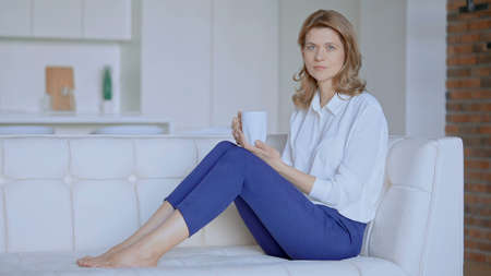 business lady sits on the couch with a cup of tea. High quality photo