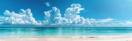 This image shows a beautiful, expansive view of a tropical ocean on a sunny day. The water is a vibrant turquoise color and is calm, with only a few small waves gently lapping at the shore. The sand is white and powdery, and the sky is a clear blue with large, fluffy white clouds floating overhead.の素材