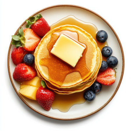 A beautifully arranged breakfast plate showcases fluffy pancakes topped with a pat of butter, drizzled with maple syrup, and accompanied by fresh berries for a delightful morning treat.の素材