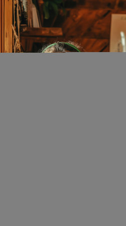 With a warm smile, a young woman in a soft sweater enjoys her time in a rustic room. The ambiance feels inviting as she connects with her tablet while wearing bright green headphones.の素材