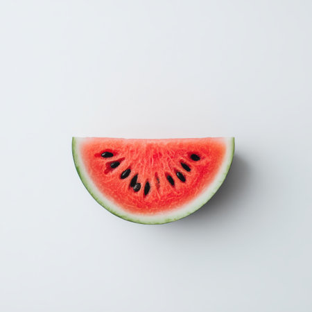 A slice of fresh watermelon reveals its juicy red interior with black seeds against a neutral backdrop. Ideal for summer gatherings or nutritious snacks that offer hydration and flavor.の素材