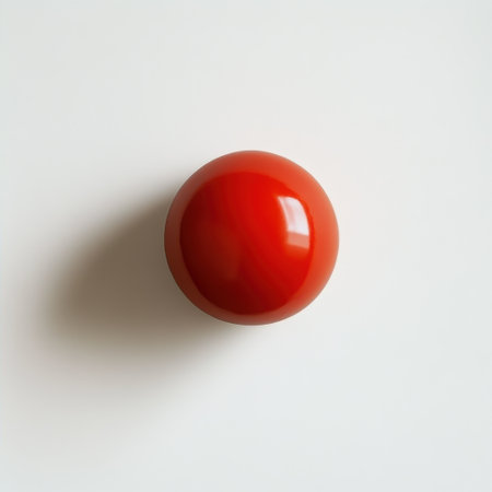 A smooth, shiny tomato rests on a clean white surface, highlighting its rich red color. This ripe fruit stands out, showing freshness and quality ideal for culinary use.の素材