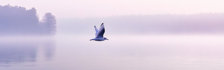A serene bird glides gracefully over a calm lake, surrounded by pastel lavender and green hues. This peaceful moment captures the beauty of nature during early morning light.の素材