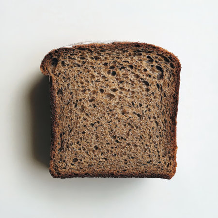 A freshly baked loaf of rye bread showcases its crisp crust and dense texture while resting flat on a clean white background, inviting a closer look and satisfying taste.の素材