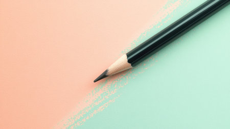 A pencil lies gently at an angle on a soft, pastel background split between peach and mint green. The minimalist arrangement enhances the delicate aesthetic of the workspace.の素材
