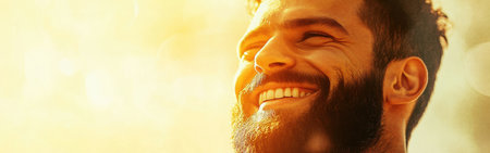 A joyful man with a beard smiles brightly, basking in soft golden light. His expression reflects warmth and happiness, creating an inviting atmosphere.の素材