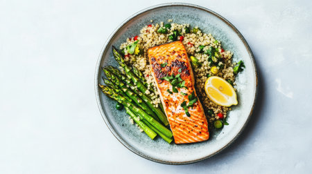 This vibrant plate features grilled salmon fillet paired with tender asparagus and quinoa salad, garnished with a slice of lemon for a fresh touch, perfect for a nutritious dining experience.の素材