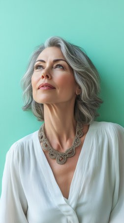 A woman with stylish gray hair stands serenely, her gaze lifted toward the ceiling.の素材