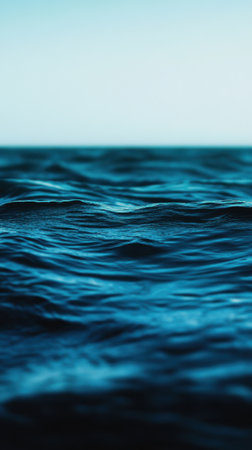 Cool aqua and indigo bokeh colors blend beautifully as gentle waves reflect the fading light during a tranquil evening by the water's edge.の素材