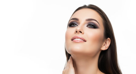 A young woman showcases a sophisticated makeup look with dark smoky eyes and soft lips, posing gracefully with a slight smile in a bright studio environment.の素材