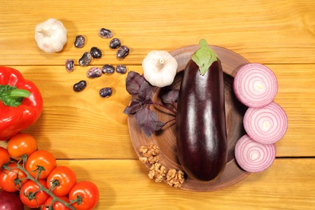 Ingredients for Salad -  vegetables and nuts lie in large pottery plate on the vintage rustic table with a rough textureの写真素材