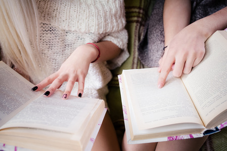 Young women's sitting on a couch and read a book, close-upの写真素材