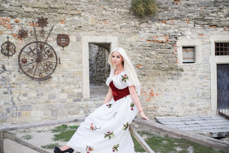 Beautiful young blond woman pose near medieval castle.の写真素材