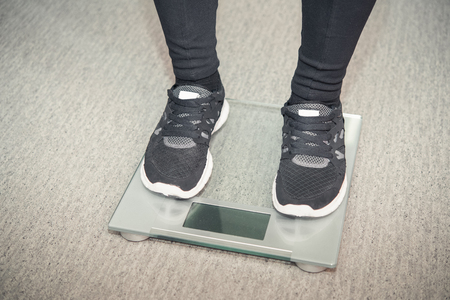 girl in sneakers standing on the scalesの写真素材