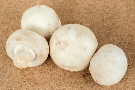 raw white mushrooms on a cork boardの写真素材