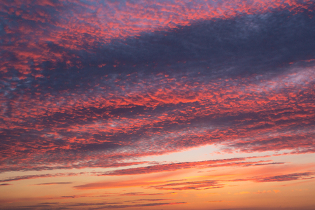 Colorful orange and blue dramatic sky with clouds and shining sunの写真素材